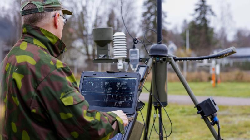 Military worker on laptop with TacMet Tactical Meteorological Observation System.