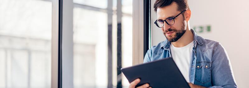 Man reading a tablet by the window